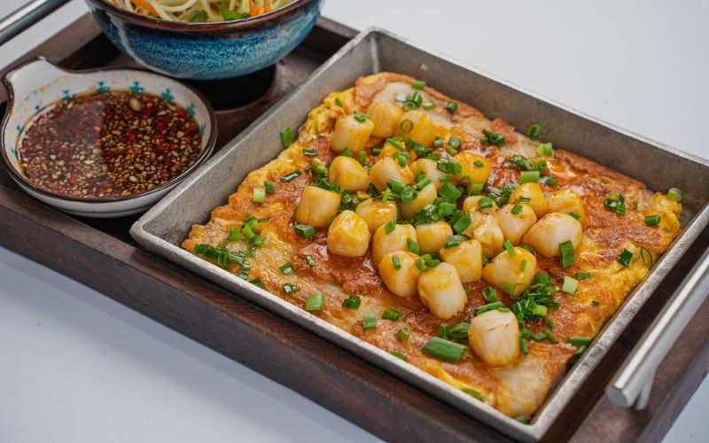 A modern fine dining interpretation of Bot Chien with scallops, featuring crispy rice cake and refined Vietnamese flavors