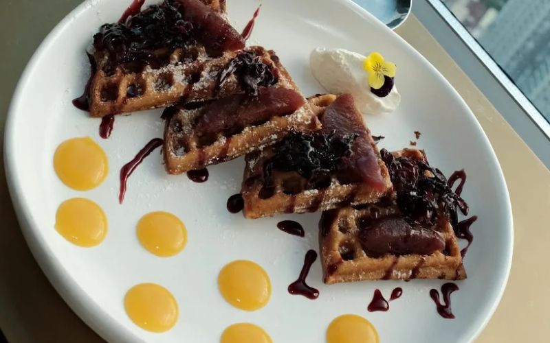 Bánh waffle trình bày đẹp mắt với sốt trái cây và kem béo trong top nhà hàng 5 sao tphcm