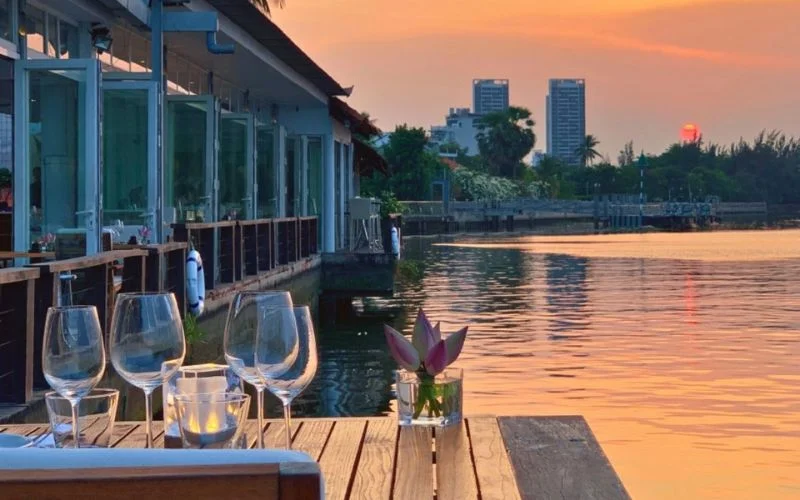 Không gian dùng bữa ven sông tại The Deck Saigon với khung cảnh hoàng hôn lãng mạn nhìn ra sông Sài Gòn