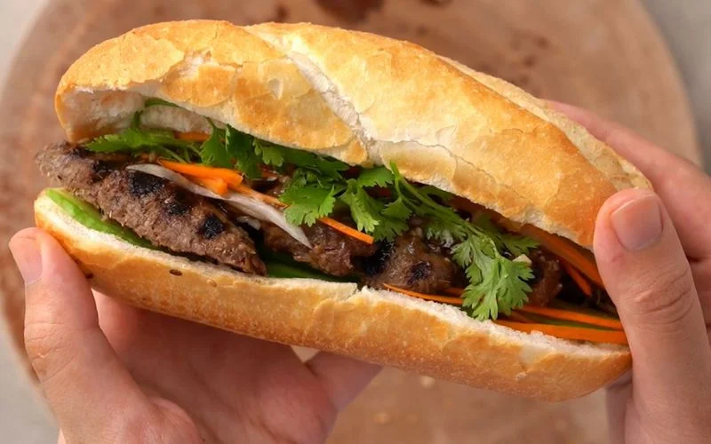Bánh mì thịt combining meats, pâté, fresh herbs, and pickled vegetables